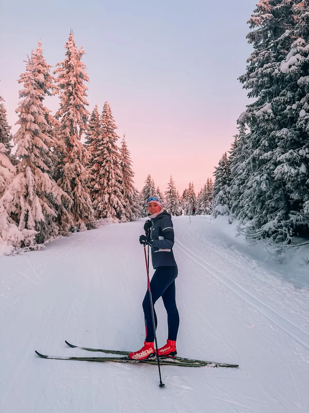 Veronica Undseth på ski i skisporet mellom snødekte grantrær