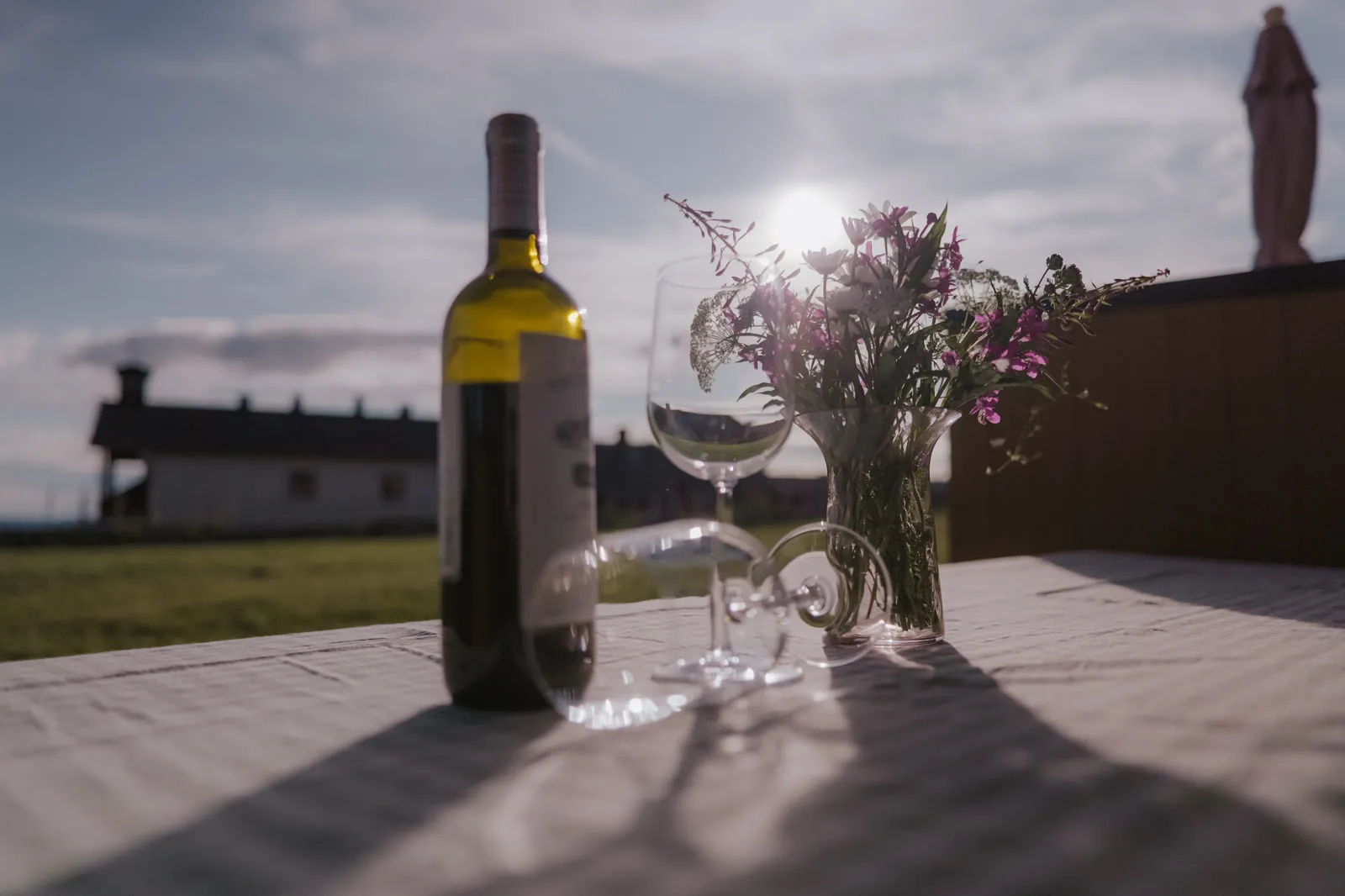 Vinflaske og glass på terrassebordet i kveldssol