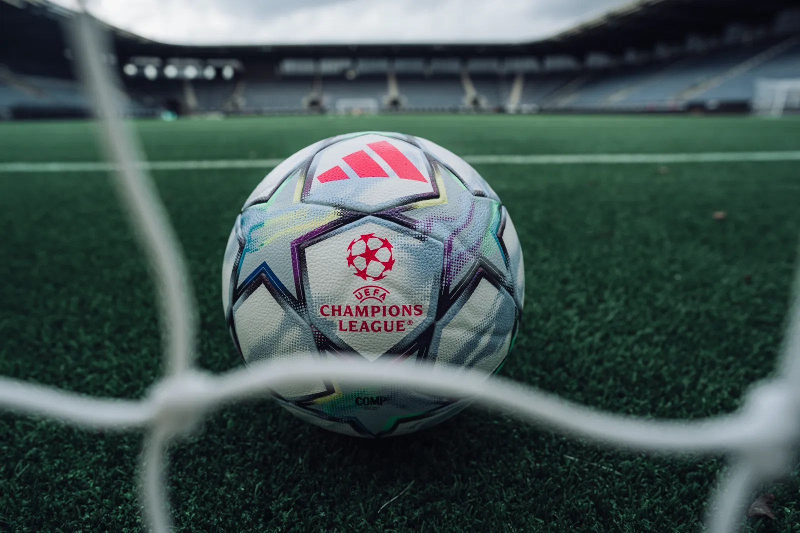 Champions League-ballen på gresset, fotografert gjennom målnettet