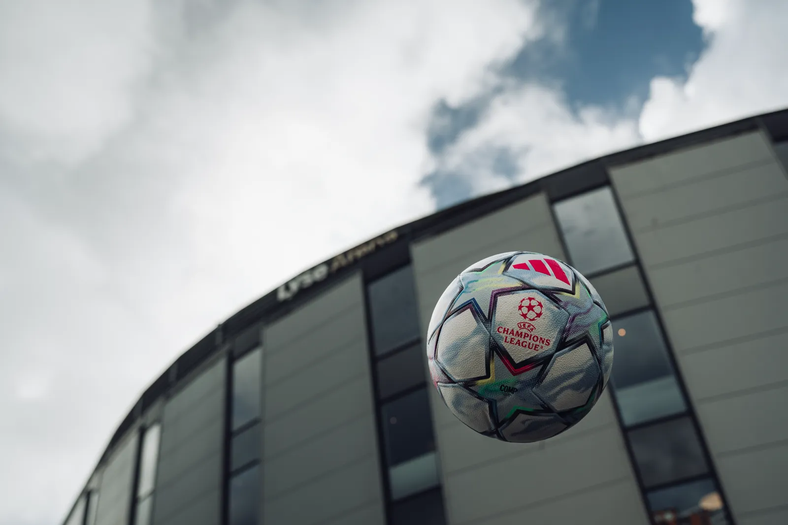 Ballen i lufta foran stadionveggen og en blå himmel