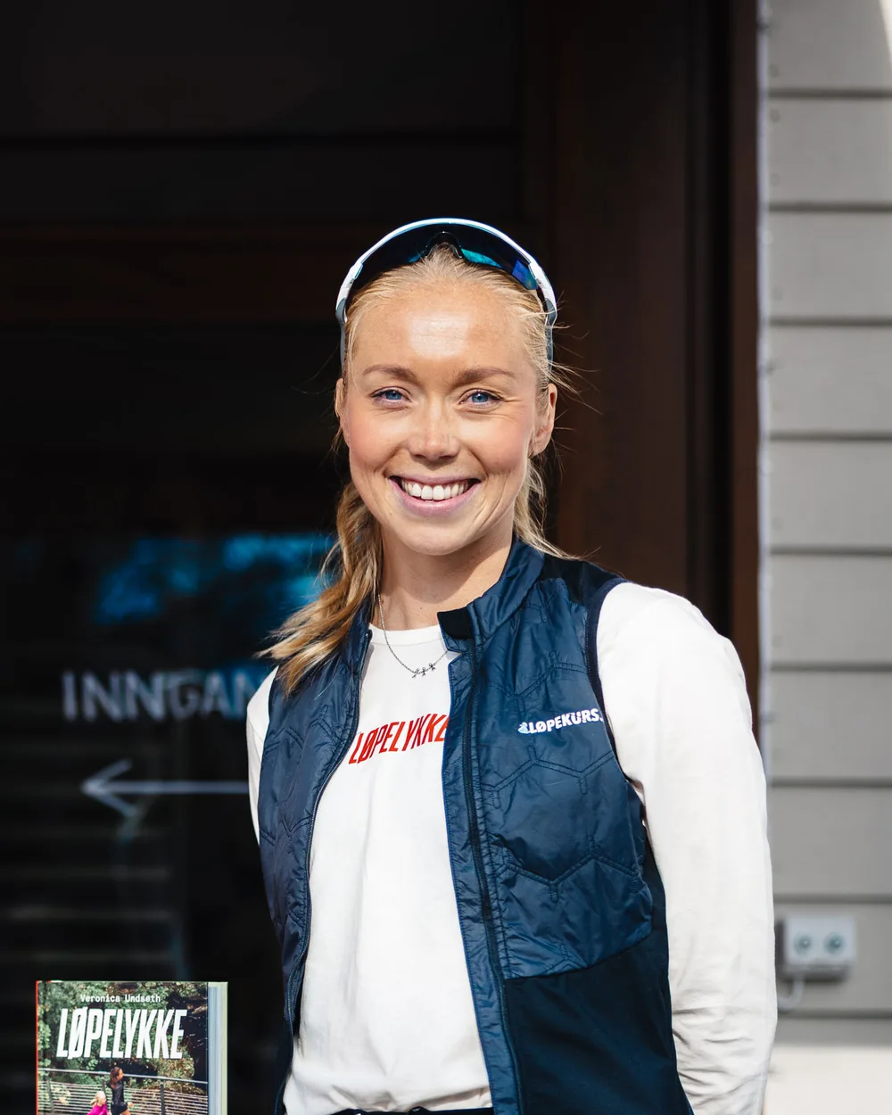 Veronica Undseth i Løpekurs-vest foran inngangen, med boka Løpelykke i hjørnet