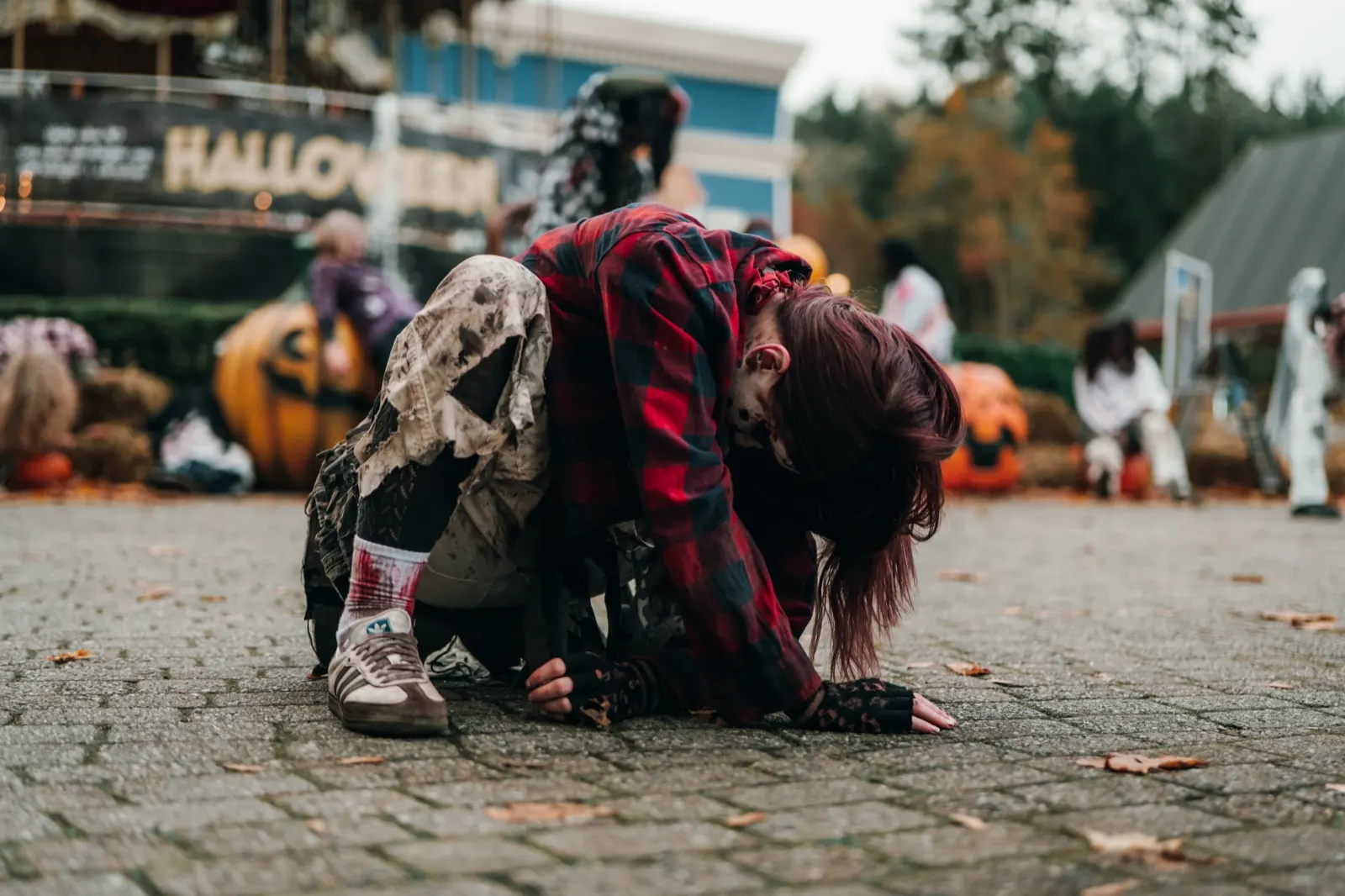 Zombie i rutete skjorte kryper over brosteinen foran halloweenpyntet i TusenFryd