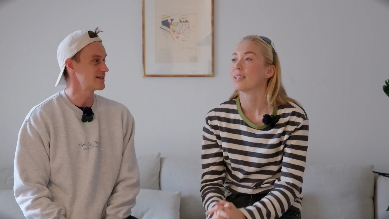 Håvard Rønning og Veronica Undseth sitter i en sofa med små trådløse mikrofoner festet i halsen.